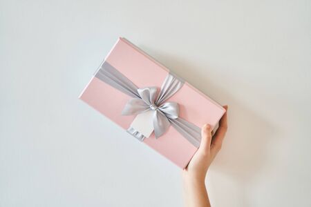 A girl holds a gift box on a white background.