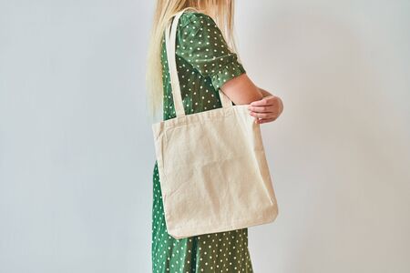 The girl is holding blank cotton eco tote bag, design mockup. Eco concept.の写真素材
