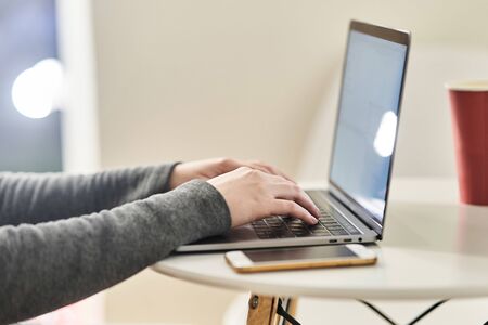 The girl works at the computer. Close-up. The girl is typing on the keyboard.の写真素材