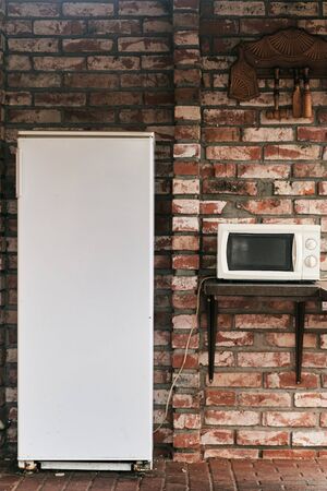 Fridge and microwave in the courtyard of a brick house.の写真素材