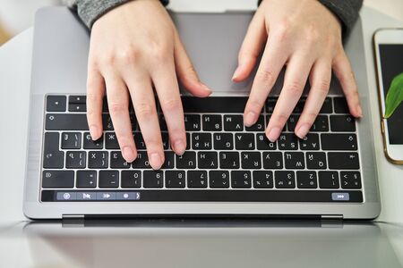 The girl works at the computer. Close-up. The girl is typing on the keyboard.の写真素材