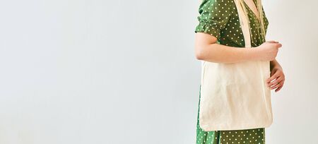 The girl is holding blank cotton eco tote bag, design mockup. Eco concept. Copy space, Banner.の写真素材