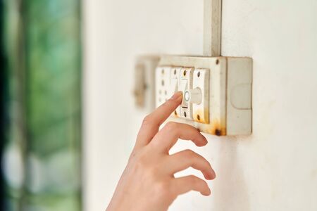 Female hand, to turn off the light, switch, side view.