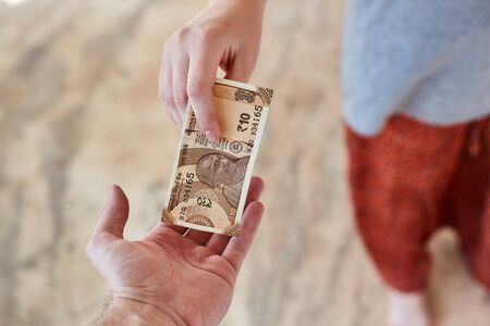 A young girl pays Indian rupees. The girl pays the man. A Girl gives money to a man.の写真素材