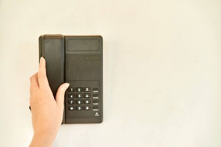 A Girl picks up the phone. Phone on the wall of a building.の写真素材