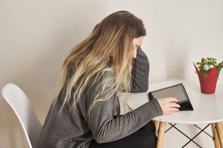 A young girl sits and works on a tablet computer.の写真素材