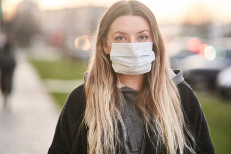 Girl in a medical mask on the background of the city. Coronavirus. Prevention of viral diseases.