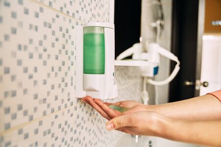 The girl squeezes the soap from the dispenser.の写真素材