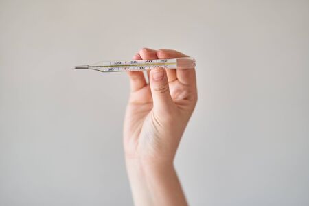 Girl holds a thermometer. High body temperature on a thermometer.の写真素材