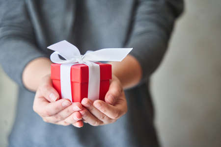 Woman holding small red present box in hands.の写真素材