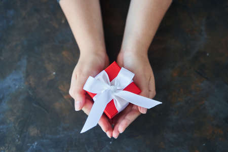 Woman holding small red present box in hands.の写真素材