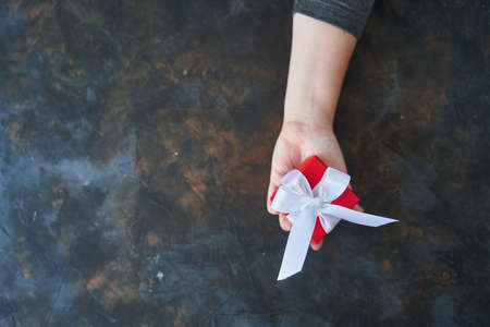 Woman holding small red present box in hands.の写真素材