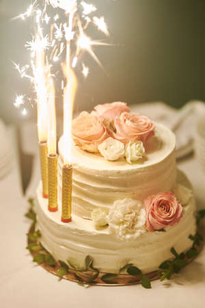 White wedding cake with burning candles at wedding celebration close upの写真素材