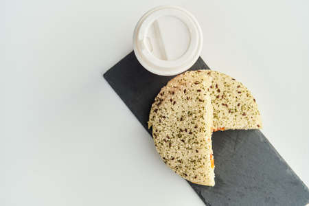 A sandwich with a red plastic glass of coffee on the table in a coffee shop.