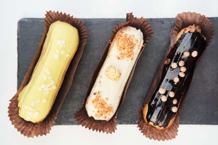 Three eclairs on a black tray top view