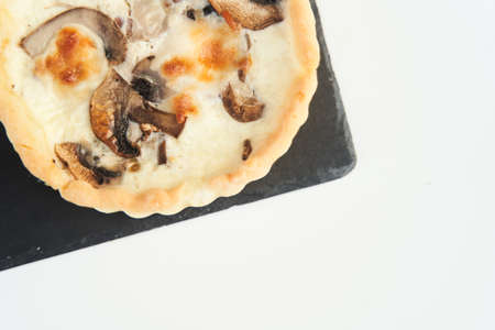 Tart with mushrooms and cheese on a white plate