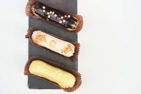 Three eclairs on a black tray top view