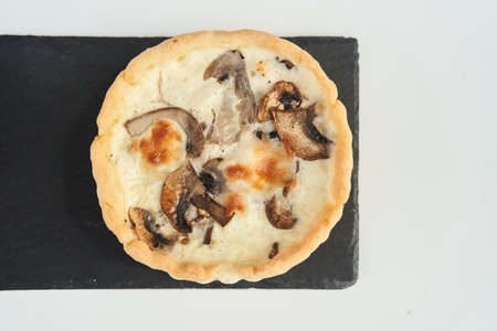 Tart with mushrooms and cheese on a white plateの写真素材