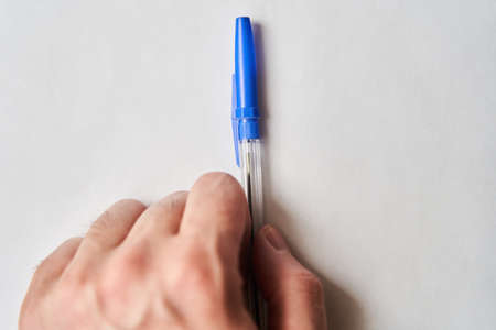 Blue plastic pen in hand of young man on white backgroundの写真素材