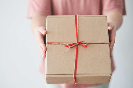 Selected focus. Girl holding a gift box with a red ribbon in her hands