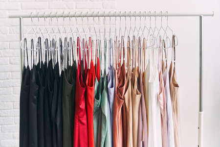 Multi-colored dresses hang on hangers in the store. Sale of womens dresses