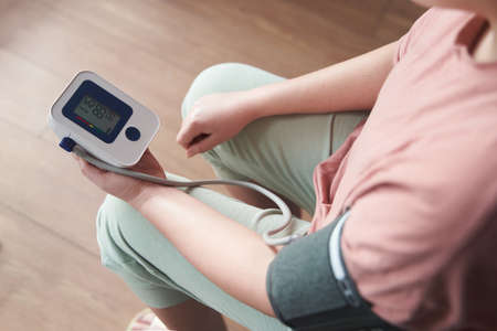 a young girl measures her blood pressure with a tonometerの写真素材