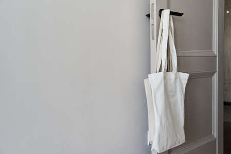 White eco friendly bag hanging on the door handle. Canvas tote bag