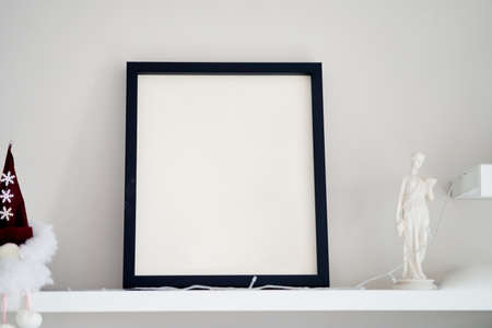Blank wooden photo frame stands in the interior on a white background. Mockup poster frame close up in home interior.の写真素材