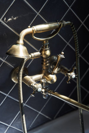 Gold faucet and shower old vintage style with grey tiles background