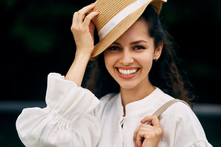 Portrait of a smiling curly-haired brunette girl in a hatの写真素材
