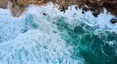 Aerial view of ocean waves crashing on rocks in Nazare, Portugalの写真素材