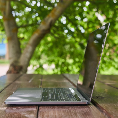 An open laptop stands on a wooden table.の写真素材