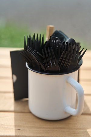 A Collection of Forks and Various Cutlery Neatly Arranged Inside a White Mug Set on a Tableの写真素材