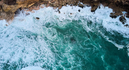 Aerial view of ocean waves crashing on rocks in Nazare, Portugalの写真素材