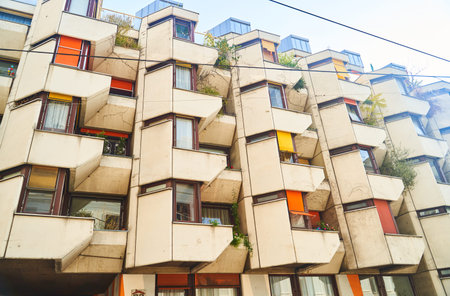 Urban apartment building with many windows, balconies, and a lush rooftop garden