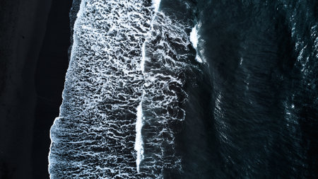 A captivating Aerial View of Waves forcefully Crashing on a stunning Black Sand Beachの写真素材