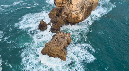 Aerial view of an old lighthouse on a cliff with a fortress on the coast of the Atlantic ocean in...