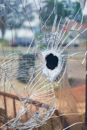 The image presents damaged glass with numerous shattered fragments and a prominent central hole