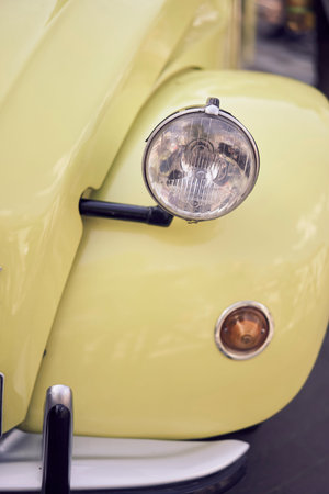 Detailed closeup view of a vintage classic car headlight featuring a shiny chrome bumper