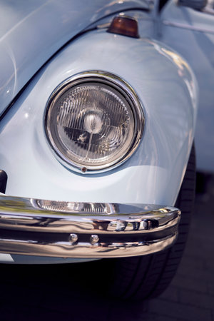 Detailed closeup view of a vintage classic car headlight featuring a shiny chrome bumperの写真素材