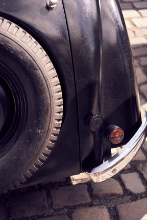 A vintage car tail light illuminates a cobbled street, embodying classic automotive aestheticsの写真素材