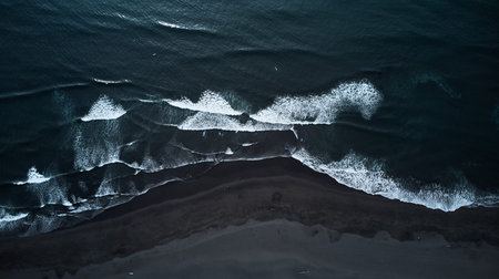 A captivating Aerial View of Waves forcefully Crashing on a stunning Black Sand Beachの写真素材