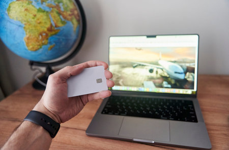 Person holds credit card in front of computer for online transaction