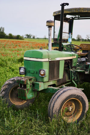 A Rustic Green Tractor Positioned Beautifully Among Vibrant Wildflowers in the Countrysideの写真素材