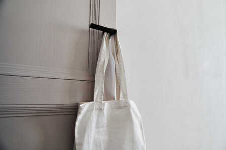 White eco friendly bag hanging on the door handle. Canvas tote bag