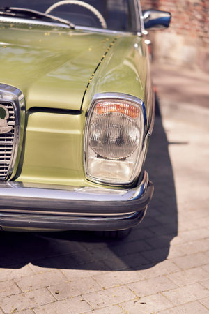Detailed closeup view of a vintage classic car headlight featuring a shiny chrome bumper