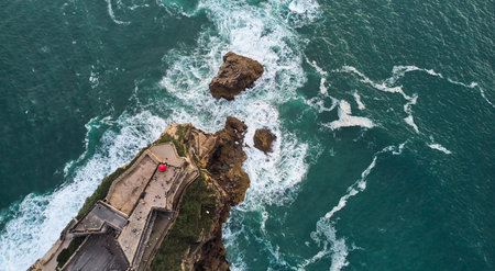Aerial view of an old lighthouse on a cliff in Nazare town, Portugal.