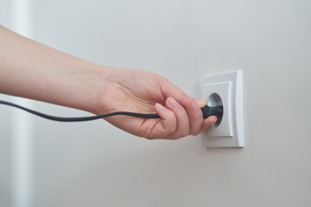 A girl inserts a plug into an outlet. Woman plugs the charger into the socket.