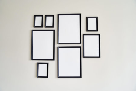 Different size framed photos hanging on the gray wall. Mockup.
