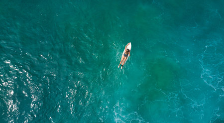 Aerial view of the ocean and surfer girl.